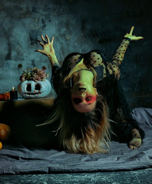 close up portrait of beautiful sexy witch with halloween makeup. red and black face painting