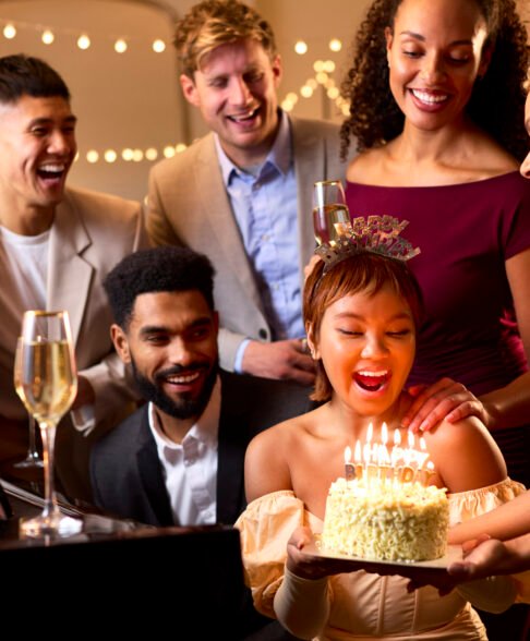 Group Of Friends Around Piano Celebrating Woman's Birthday With Cake