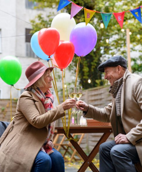 Portrait of happy senior couple with wine in outdoor cafe in city, celebrating birthday.