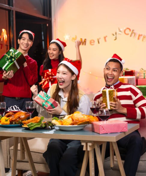 Two handsome young men and two beautiful young women wearing Christmas hats laughing joyfully