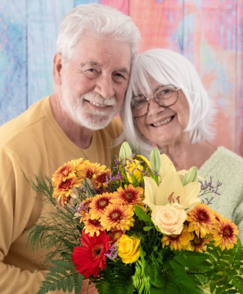 Valentine's day. Smiling senior couple exchanging a flower bouquet. Romantic portrait of elderly caucasian couple. Woman receives flowers as present from husband