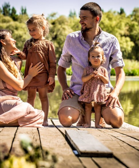 young family on the pier near the lake playing with young daughters